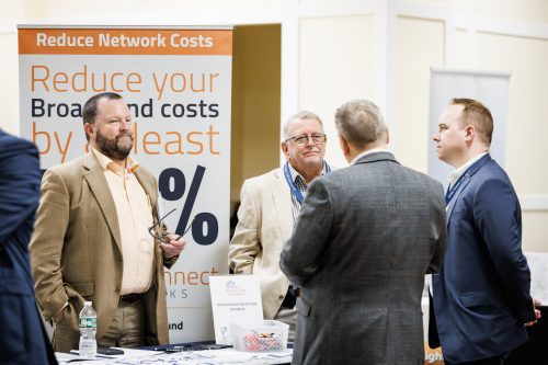 HealthConnect Networks team members standing at an exhibit booth promoting Healthcare Connect Fund funding opportunities at a healthcare conference.
